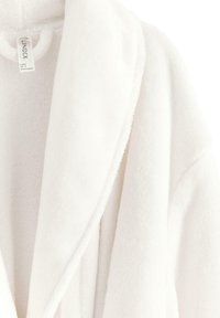 Accappatoio bianco in fleece con una finitura morbida e testurizzata, colletto a scialle e senza chiusura visibile. Etichetta attaccata all'interno dell'area del collo.