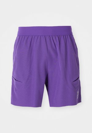 Lilla sportsbukser med elastisk talje, to sidelommer og en glat tekstur. Simpelt design med et logo på den nederste front.