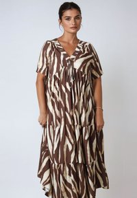 Brown and cream tiered dress with a V-neck, short sleeves, and tie detail at the neckline. Features a zebra stripe pattern and flowing silhouette.