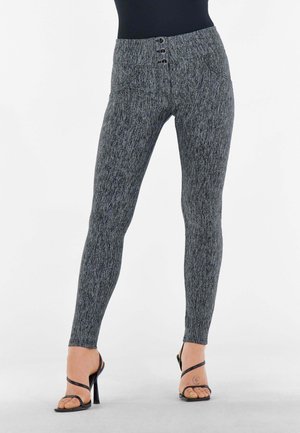 Leggings grigi-neri a vita alta in maglia con un motivo testurizzato e tre bottoni decorativi in vita. Indossati con sandali neri con tacco.