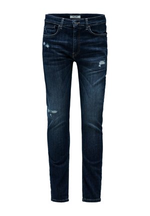 Vaqueros ajustados de color azul oscuro con ligeros parches desgastados en el muslo y la rodilla, con bolsillos frontales y trabillas para el cinturón.