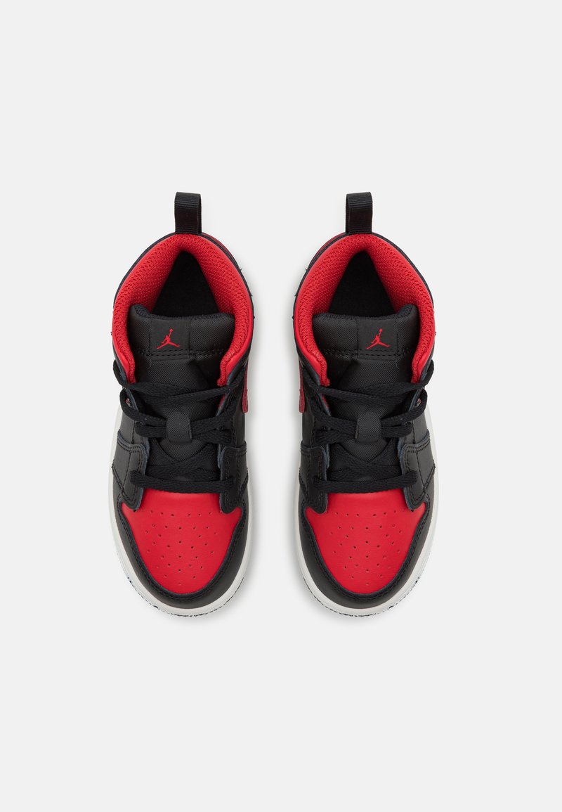Chaussures de sport noires et rouges avec une tige en cuir et en maille, dotées d'une boîte à orteils rouge perforée, de lacets noirs et d'un soutien de la cheville bien marqué.