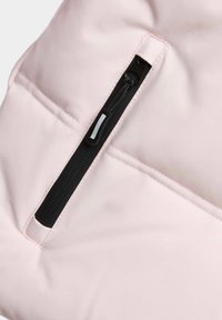 Bolsita de tela rosa claro con un zipper negro. La superficie es suave con costuras visibles y un diseño de bolsillo con solapa.