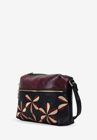 Bolso de hombro de cuero con una base negra acolchada, parte superior burdeos y un diseño floral bordado en rojo, dorado y crema. Cuenta con un cierre de cremallera dorado.