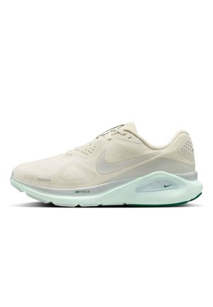 Lichtbeige Nike hardloopschoen met mesh bovenwerk, gedempte zool en Nike-logo aan de zijkant en tussenzool, weergegeven op witte achtergrond.