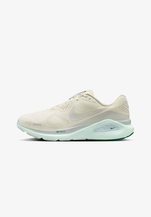 Lyse beige Nike løbesko med mesh-øverdel, polstret sål og Nike-logo på siden og mellemsålen, vist på hvid baggrund.
