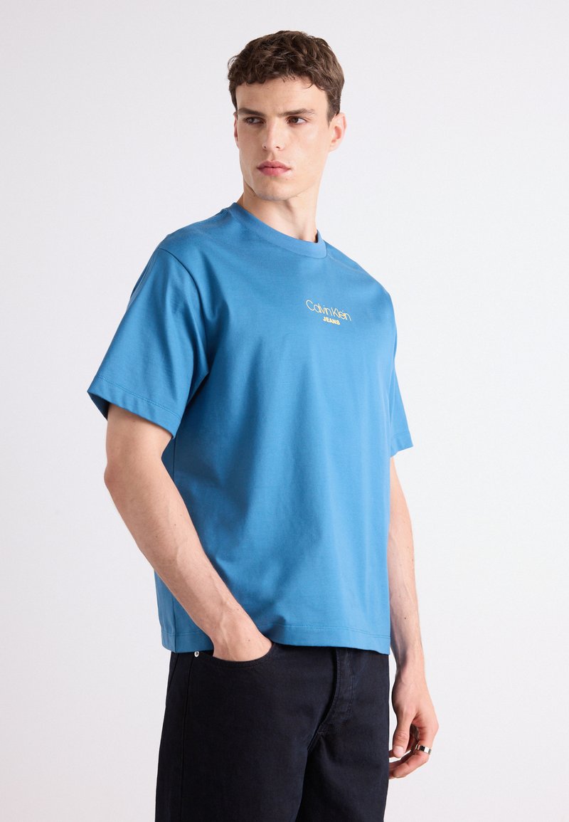 Kék pamut póló rövid ujjal és kerek nyakkivágással, az elején hímzett "Calvin Klein Jeans" logóval.