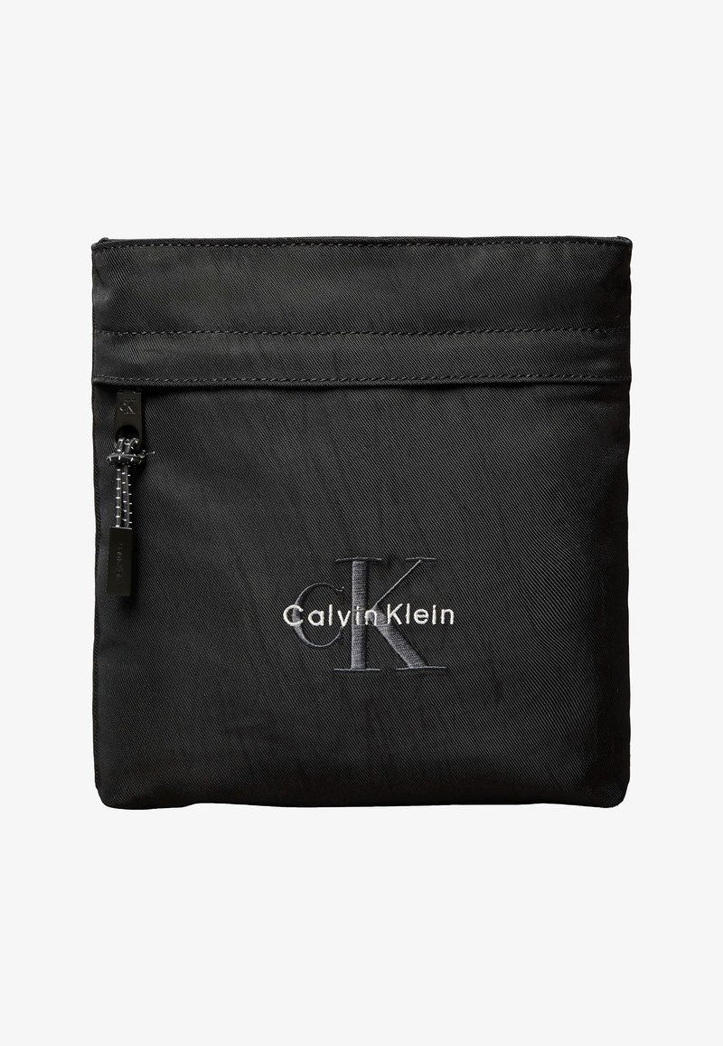 Μαύρο νεσεσέρ Calvin Klein με τσέπη με φερμουάρ μπροστά και κεντημένο μεγάλο λογότυπο "CK" σε γκρι και λευκό σε απλό φόντο.