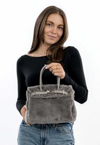 Grå faux fur håndtaske med et struktureret design, der har grå læderhåndtag og sølvhardware med en metallisk detalje på lukningen.
