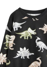 Svart sweatshirt med färgglada dinosaurieskelettmönster i nyanser av grönt, vitt och beige. Klassisk rund hals med ribbade ärmslut.