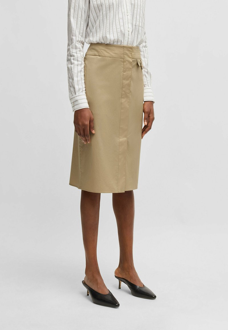 Khaki pencil skirt made of smooth fabric, featuring a side tie detail, knee-length cut, and a clean, tailored silhouette.