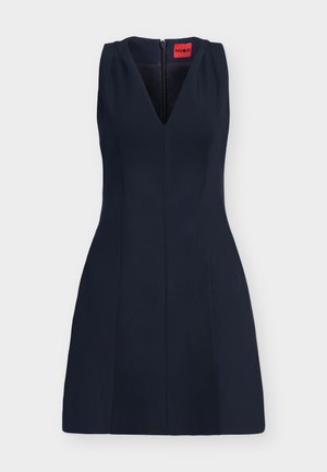 Robe sans manches bleu marine foncé avec encolure en V, taille cintrée et fermeture éclair au dos, comportant une étiquette de marque HUGO rouge à l’intérieur du col.