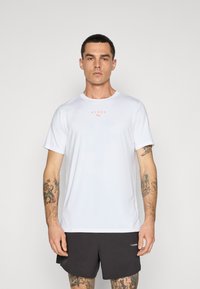 Hvid atletisk t-shirt i letvægtsstof, med korte ærmer, rund halsudskæring og et lille orange "HYROX" logo med sorte detaljer.