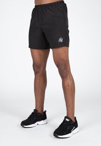 Crne atletske kratke hlače s elastičnom trakom u struku i bočnim džepovima, sivoj gorilla logo. Uparene s crnim sportskim tenisicama.
