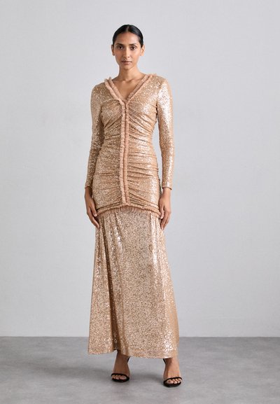 Robe en sequins rose doré avec un décolleté en V et des manches longues, présentant une texture plissée et une finition en volants au centre. Modèle longueur sol.