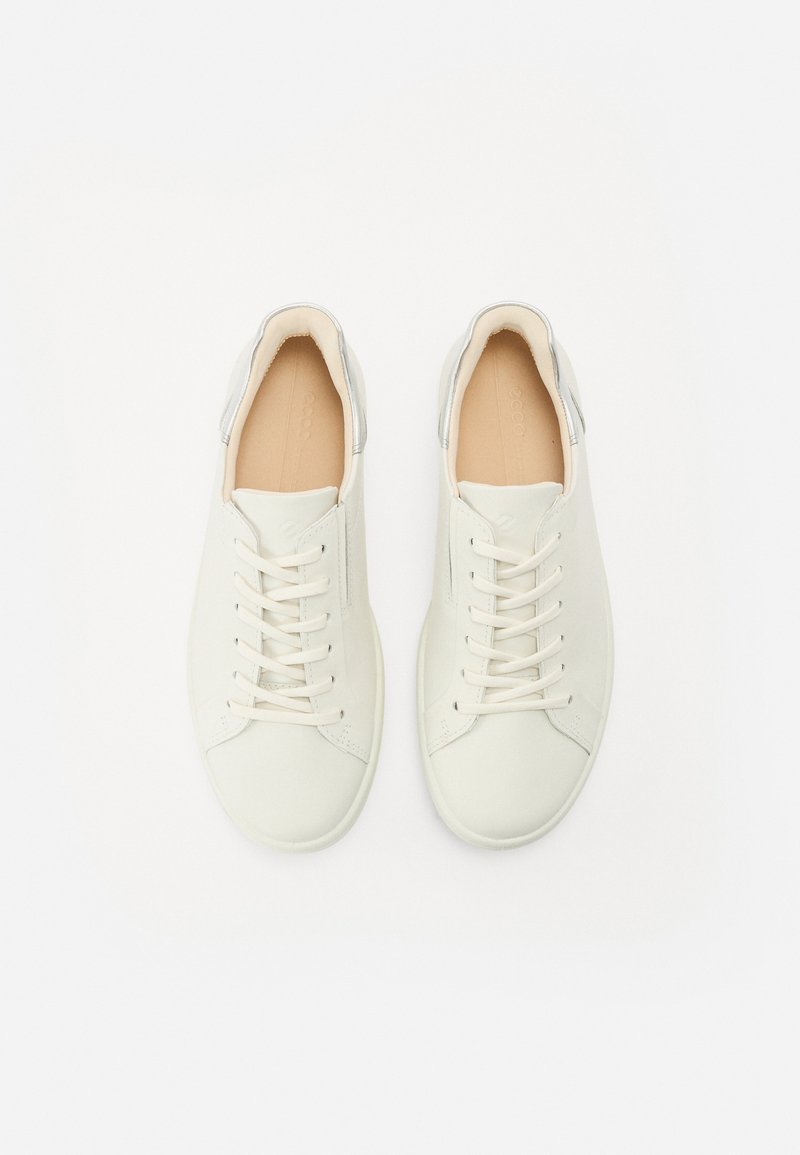 Białe skórzane sneakersy z beżowymi akcentami, płaskimi sznurowadłami, minimalistycznym designem i srebrnym detalem na pięcie, widziane z góry.