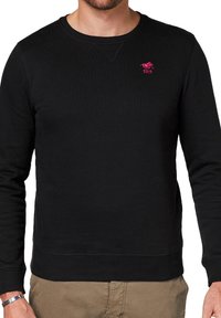 Czarny, prążkowany sweatshirt z okrągłym dekoltem, z małym różowym logo. Gładka tekstura i dopasowany krój, z długimi rękawami i pasem.