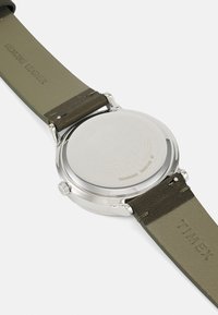 Montre Timex avec boîtier en acier inoxydable, forme ronde, bracelet en cuir véritable vert, finition texturée et fond de boîtier gravé.