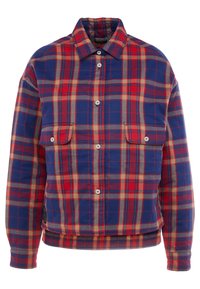 Veste à manches longues boutonnée avec motif à carreaux rouge, bleu et beige, dotée de deux poches à rabat avec boutons sur le devant.