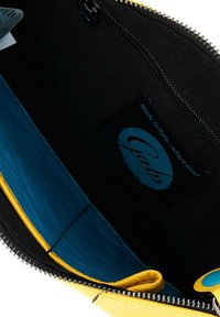 Interno di una borsa in pelle gialla con fodera blu, sezioni in tessuto nero e una tasca con zip. Marchio Gabs visibile su un'etichetta.