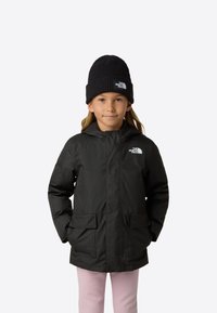 Černá voděodolná bunda s kapucí, se zipem vpředu a dvěma velkými kapsami na klopě. Nosit s černou pletenou čepicí, přes růžové kalhoty.