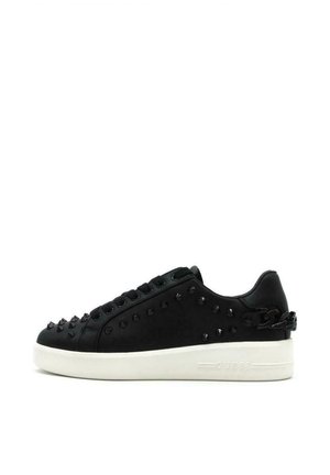 Sneaker nera con accenti borchiati, parte superiore in pelle liscia, suola in gomma bianca, design con lacci e dettaglio della catena laterale. Logo del brand sul tallone.