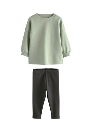 Langærmet lysegrøn top med ribmanchetter kombineret med højtaljede sorte leggings, begge lavet af blødt strikstof.