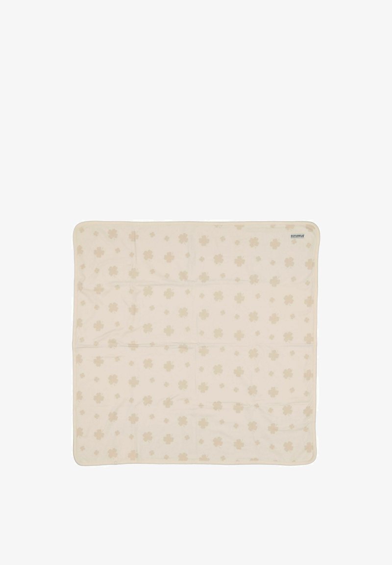 Valkoinen peitto, jossa on heleä kukkakuosi, joka on hiukan tummempaa valkoista. Pehmeä tekstuuri ja pyöristetyt kulmat.