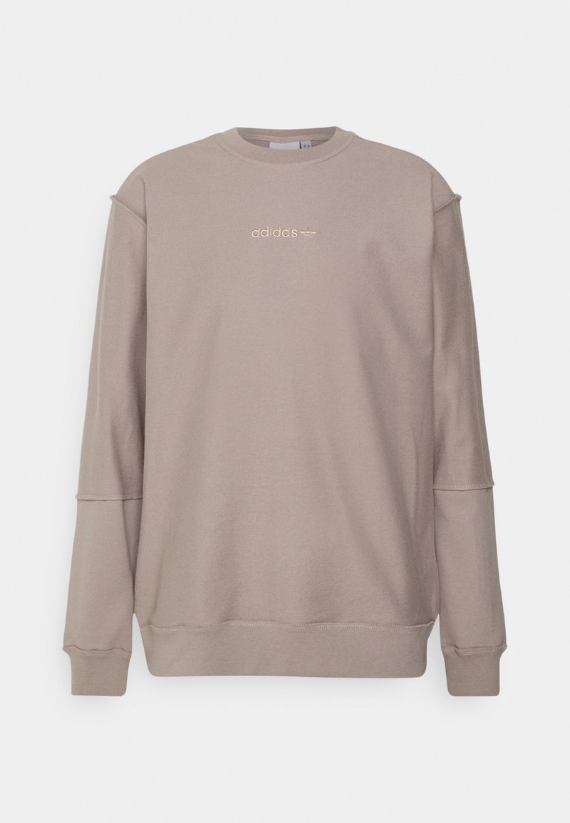 Sudadera marrón clara con cuello redondo, puños acanalados y un pequeño logo bordado en dorado. Textura suave, corte relajado, diseño minimalista.