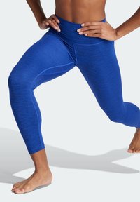 Leggings sportivi blu con vita alta, caratterizzati da una texture melangiata e un design aderente, che si estendono fino a metà polpaccio.
