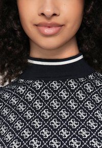 Pulover de marin cu model geometric alb și detalii cu logo; guler cu nervuri cu dungi albe și bleumarin, țesătură texturată.