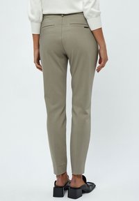 Pantaloni beige su misura con una trama liscia, dotati di due tasche posteriori e una vestibilità slim. Abbinati a sandali neri con tacco a blocco.