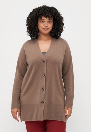 Brun kort cardigan laget av mykt materiale, med V-hals, fem knapper og ribbede mansjetter. Designet er løs passform med sidesplitter.