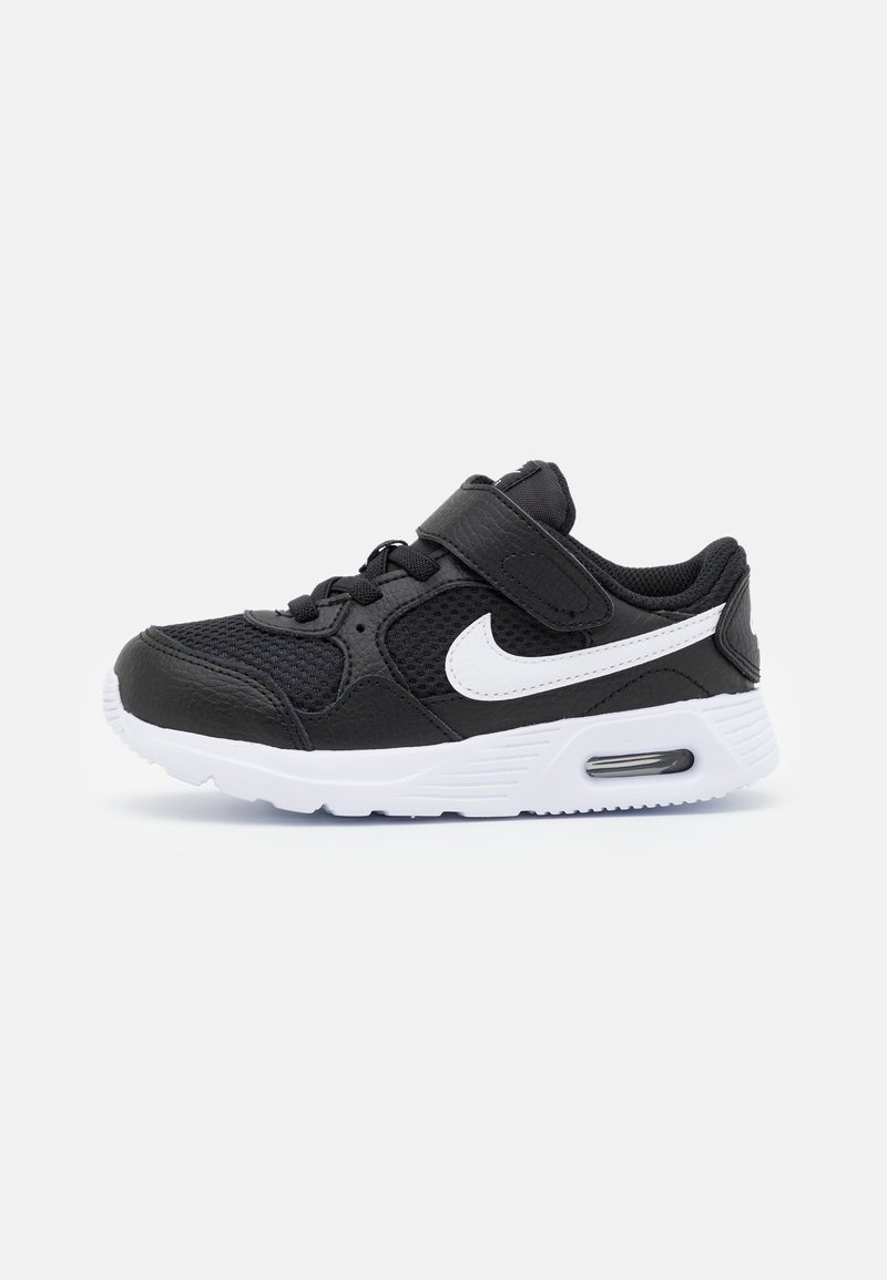 Zapato deportivo negro con acentos blancos, parte superior de malla y sintético, correa ajustable, punta redonda y amortiguación de aire visible en la suela.