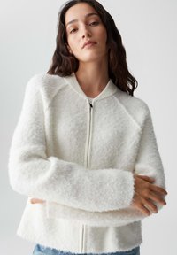 Witte, fluffy zip-up sweater met een ribgebreide kraag en manchetten. Beschikt over een relaxte pasvorm en een textuurstof. Eenvoudig, minimalistisch design.