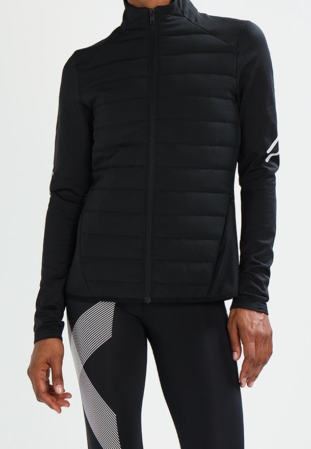 Personne portant une veste matelassée noire avec des manches longues noires et un legging noir avec un motif de rayures diagonales blanches.
