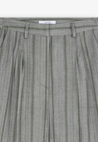 Grå herringbone-byxor med gröna ränder, med framveck, en midja med bältesöggor och en etikett med "SCALPERS" på insidan.