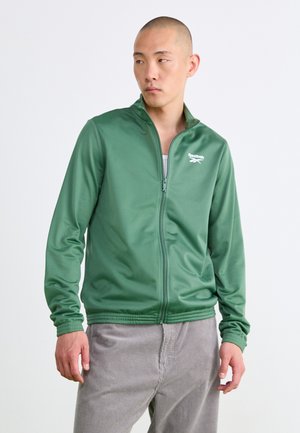 Roheline tõmblukkudega spordijakk, mis on valmistatud siledast kangast, kõrge kaelusega, soonikkoes mansettide ja vasakul rinnal oleva valge logoga.