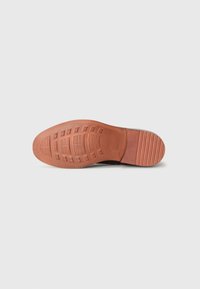 Suola di scarpa in gomma marrone, caratterizzata da motivi testurizzati e scanalature per una maggiore presa. Bordi lisci con un leggero tacco. Design della superficie piatta.