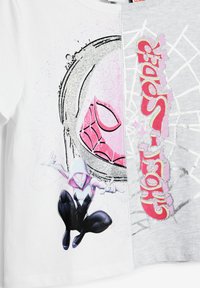 Vit och grå t-shirt med en färgglad grafik av ett spidermärke, en karaktär i svart och rosa, samt text med glittrande detaljer.