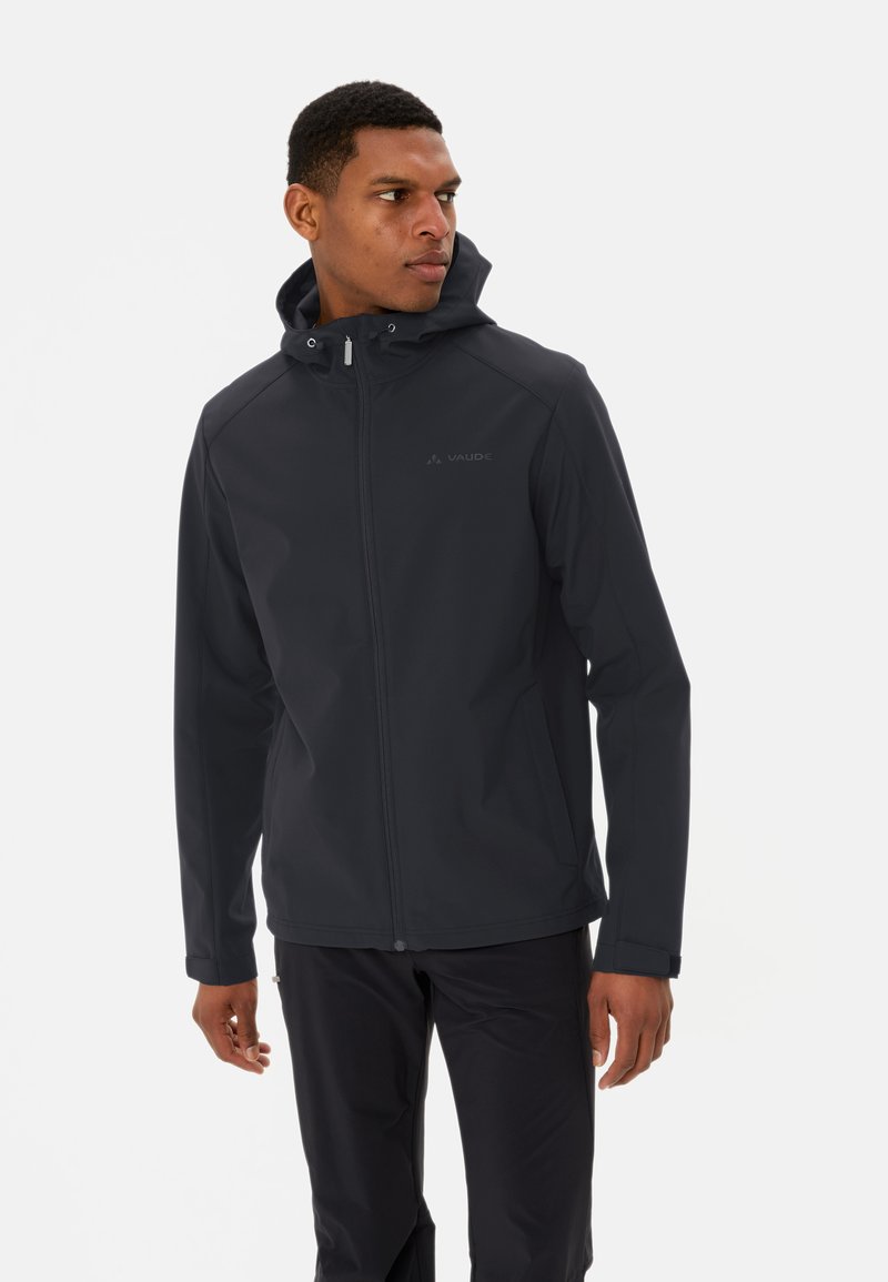 Veste noire imperméable avec capuche réglable, fermeture éclair à l'avant, texture lisse et détail logo réfléchissant sur la poitrine gauche.