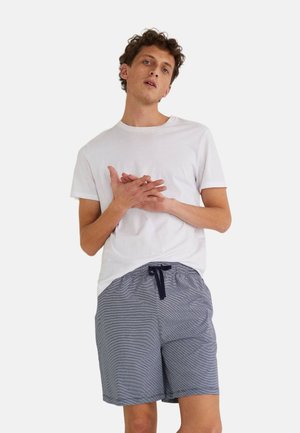 T-shirt blanc à manches courtes associé à un short rayé bleu marine avec une taille élastique et un cordon de serrage. Coupe décontractée et tissu léger.