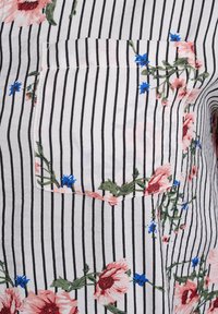 White fabric with black vertical stripes, featuring a floral pocket design with pink and blue flowers, and green leaves. Smooth texture.