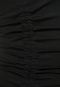 Tela negra con una textura fruncida que se extiende verticalmente. Superficie lisa con secciones recogidas que crean dimensión e interés visual.