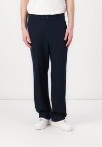 Navy blue, lightweight trousers with a straight fit, featuring a button closure and slanted pockets, paired with white sneakers.