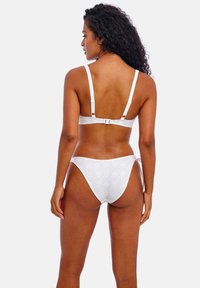 Witte bikiniset met een gestructureerde stof en geometrische patronen. Verstelbare banden en een haaksluiting op de rug van de top.