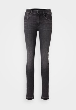 Jean skinny noir en denim, avec poches avant, fermeture à bouton et ourlets effilochés au niveau de la cheville. Texture lisse avec un léger dégradé.