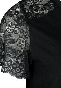 Černý top s průhlednými krátkými rukávy z černé krajky s květinovými vzory, hladká textura v těle a kulatý výstřih.