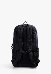 Mochila negra con correas de malla acolchadas, asa superior, hebillas frontales ajustables y bolsillos laterales para almacenamiento adicional. Acabado de material suave.