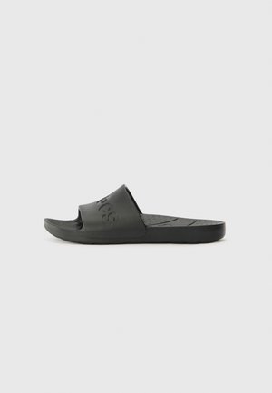 Schwarze Rutschsandalen aus Gummi mit einem breiten Riemen mit eingeprägtem Logo, strukturiertem Fußbett und flacher Sohle.